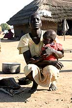 Elizabeth Anyeith squatting on the ground holding her baby