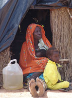 sudanese woman sitting with her children on the ground inside her refugee tent